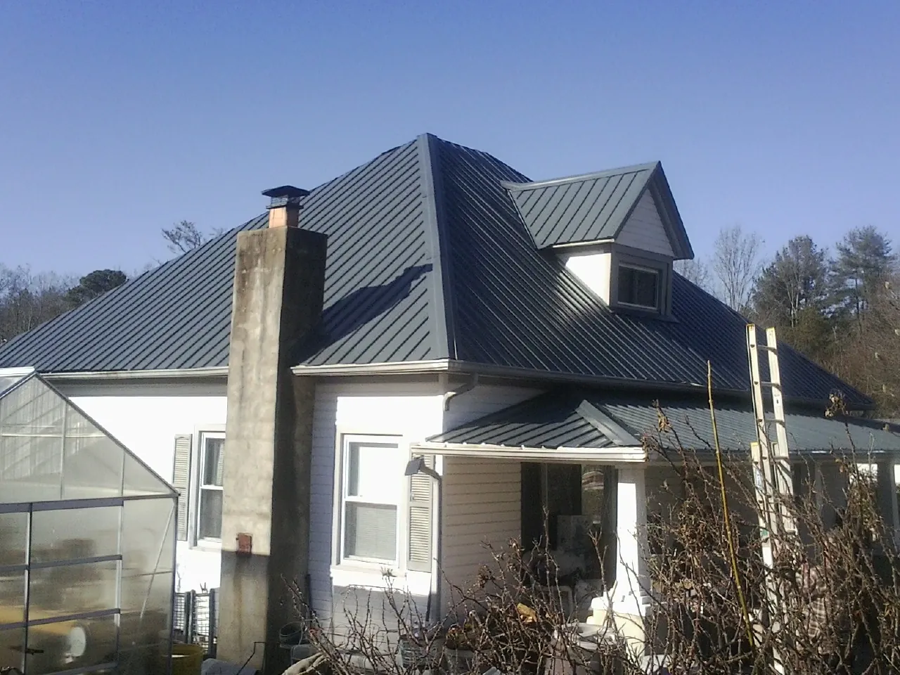 Dark blue standing seam metal roof on a white farmhouse with dormer — Slate & Tile Roof Repair by Roofing Brothers in Midlothian