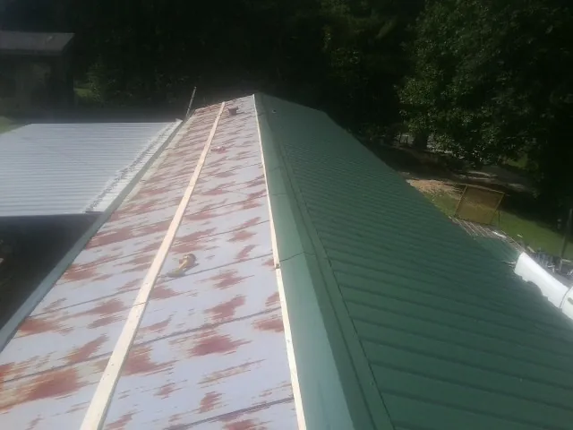 Old rusted panels beside newly installed green metal roofing — Wind Damage Roof Repair by Roofing Brothers in Midlothian