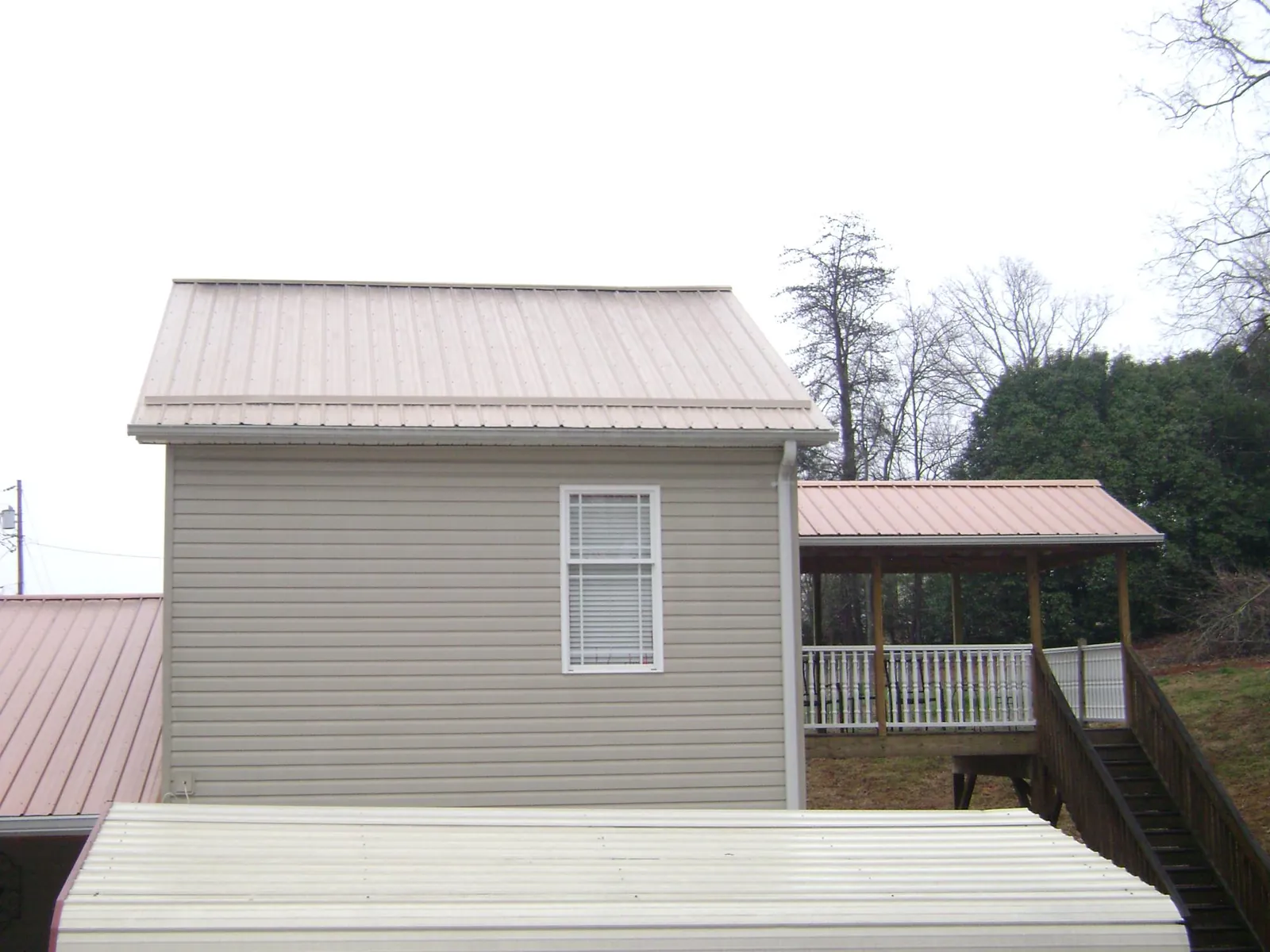 Tan metal roofs on a two story addition and attached porch, from a Roof Replacement job in Midlothian